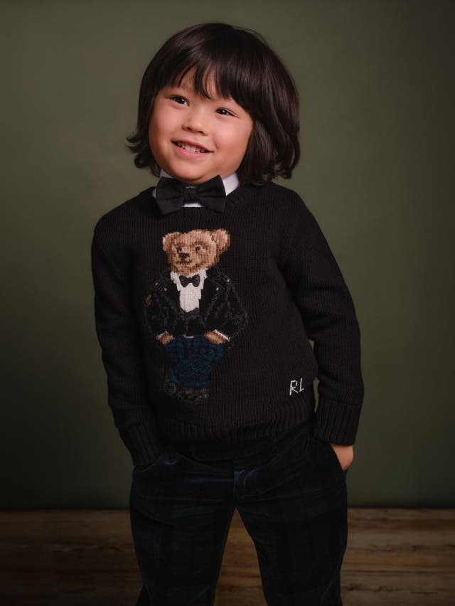Young boy in navy polo bear jumper with bow tie and smart trousers 