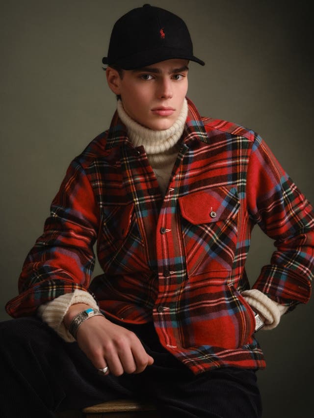 Man in red plaid shirt with cream roll neck jumper underneath and black jeans 