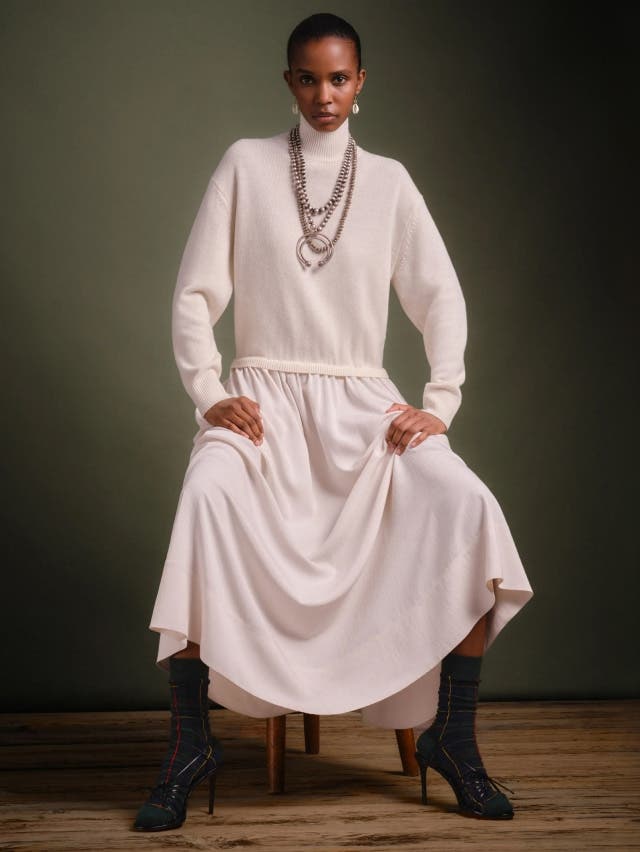 Women in white roll neck jump, white skirt and black boots 